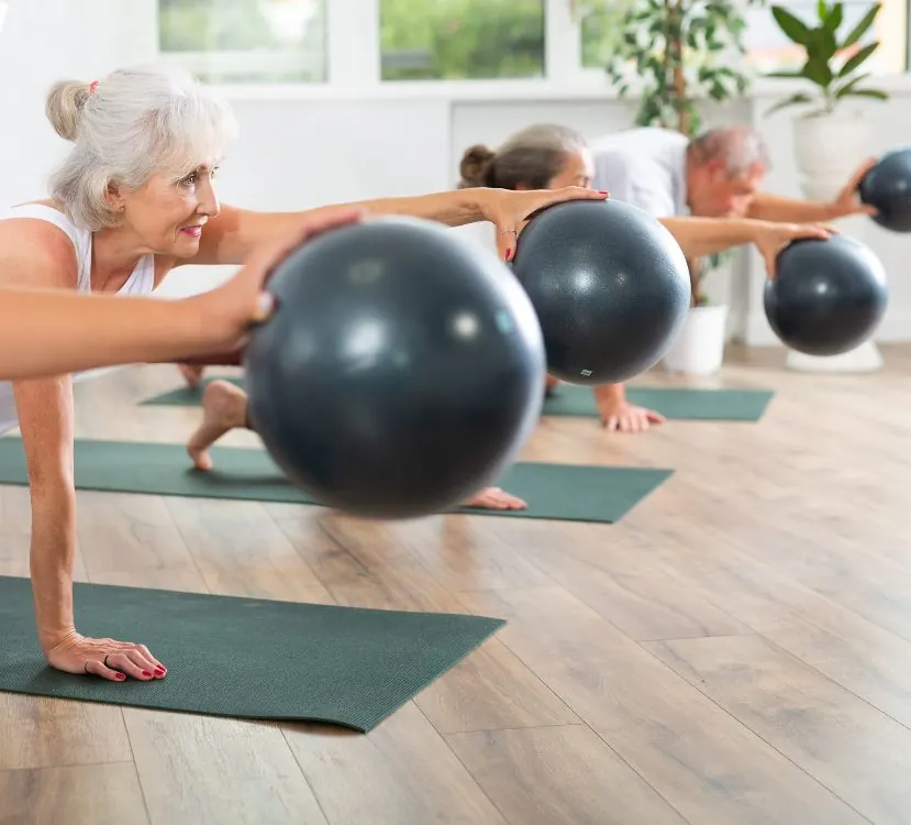 Older adults exercising with small balls during a Pilates session