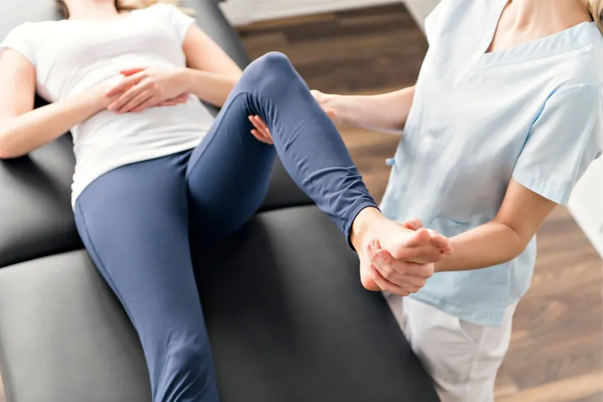 Physiotherapist treating a patient's back and hip on a treatment couch